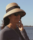 Picture of woman wearing rattan bell hat with black ribbon and bow. 