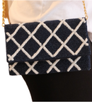 picture of navy and white lattice trim bag on persons shoulde3r with chain hanging down. 